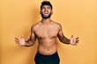 © Krakenimages.com - Arab man with beard wearing swimwear shirtless crazy and mad shouting and yelling with aggressive expression and arms raised. frustration concept.