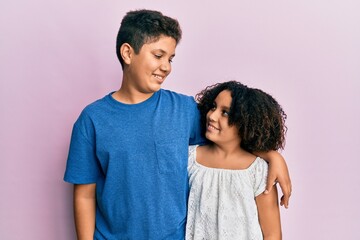 Wall Mural - Young hispanic family of brother and sister wearing casual clothes together smiling looking to the side and staring away thinking.