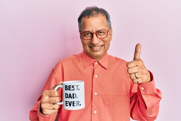 Sticker - Middle age indian man drinking mug of coffee with best dad ever message smiling happy and positive, thumb up doing excellent and approval sign