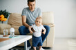 © Drazen - Cute baby boy making his first steps with help of father at home.