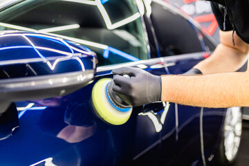 Wall Mural - Car detailing - Man with orbital polisher in repair shop polishing car. Selective focus..