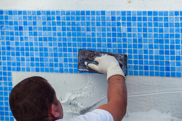 Laying tile in the pool. Pool repairing work.