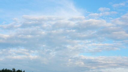 Wall Mural - evening 4k cloudscape. blue peaceful sunset sky with soft last sunlight through white fluffy clouds