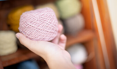 Wall Mural - Female hand holding the pink yarn ball with the earth tone yarn in the wooden cupboard  prepare for made Crochet and knitting