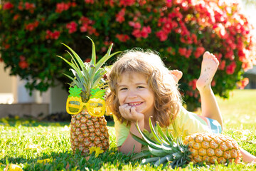 Cute kid with pineapple. Fresh tropical fruits for kids. Healthy lifestyle with fresh organic fruits.