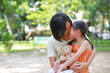 © zilvergolf - Portrait of happy Asian mother cuddle daughter and hugging teddy bear doll in the garden. Mom and child girl with love and relationship concept.