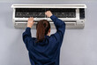 © geargodz - female technician service using screwdriver to repairing air conditioner indoors