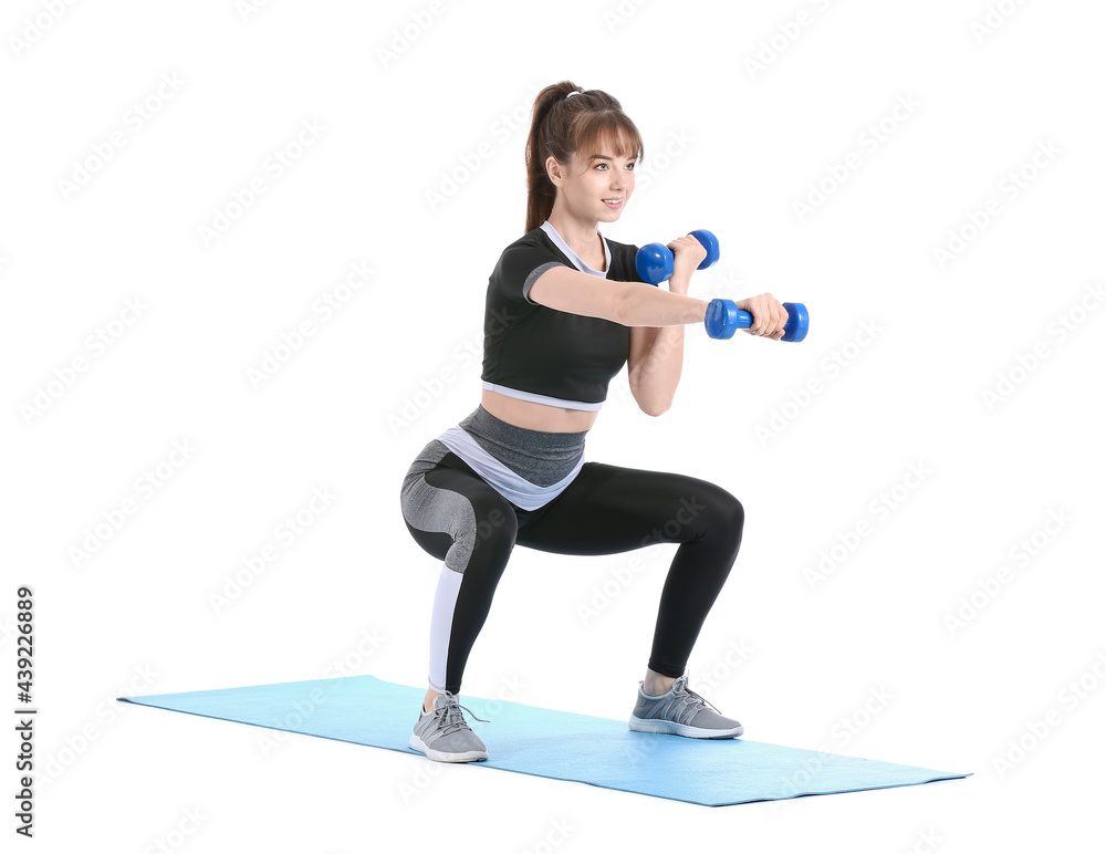Sporty young woman training with dumbbells on white background