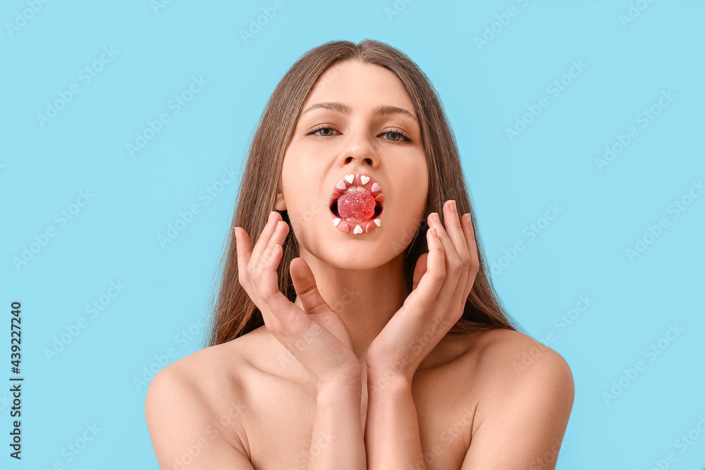 Beautiful young woman with creative makeup and candy on color background