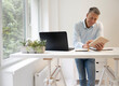 © epiximages - business man with blue shirt is standing behind high standing table and is working with his tablet