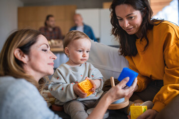 Happy multigeneration family playing with small baby indoors at home, visiting concept.