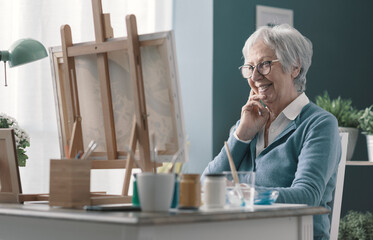 Wall Mural - Happy senior lady looking at her finished artwork