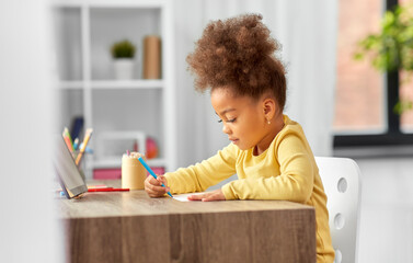 Poster - childhood, creativity and art concept - little african american girl with felt pen drawing picture on paper at home