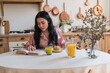 © LIGHTFIELD STUDIOS - young asian girl in silk pajamas reading book while having breakfast in kitchen