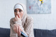 tense arabian woman in hijab watching film at home