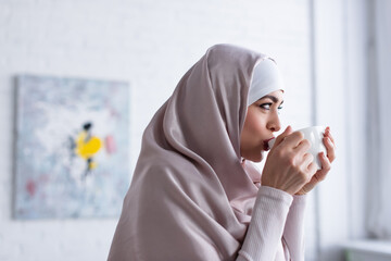 Wall Mural - pretty muslim woman in hijab drinking tea at home