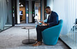 © Wavebreak Media - African american businessman holding a document using laptop while sitting on chair at modern office