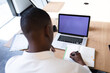 © Wavebreak Media - African american businessman with laptop taking notes while sitting in meeting room at modern office