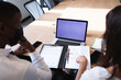 © Wavebreak Media - Diverse businessman and businesswoman wearing face masks discussing over a document at office