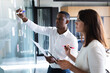 © Wavebreak Media - Diverse businessman and businesswoman writing on memo notes on glass board at modern office