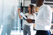 © Wavebreak Media - Diverse businessman and businesswoman writing on memo notes on glass board at modern office