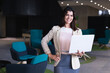 © Wavebreak Media - Portrait of caucasian businesswoman holding a laptop smiling while standing at modern office