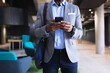 © Wavebreak Media - Mid section of african american businessman using smartphone while standing at modern office