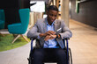 © Wavebreak Media - Disabled african american businessman using smartwatch while sitting on wheelchair at modern office
