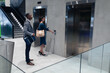 © Wavebreak Media - Caucasian businesswoman holding smartphone pressing the lift button at modern office
