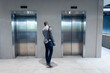 © Wavebreak Media - Rear view of african american businessman waiting for the lift at modern office