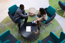 Overhead View Of Diverse Businessman And Businesswoman Shaking Hands At Modern Office