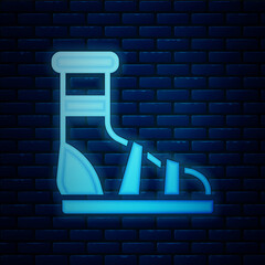 Poster - Glowing neon Slippers with socks icon isolated on brick wall background. Beach slippers sign. Flip flops. Vector