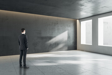 Wall Mural - thoughtful young businessman standing in concrete interior with mock up place and windows with dayli