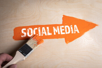 Canvas Print - Social Media concept. Orange arrow on a wooden background
