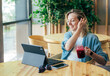 © Ilona - Young happy cheerful laughing blonde working on a laptop sitting at a table in a cozy cafe and drinking berry smoothie