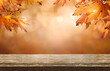 © Duncan Andison - A wood table product display with copyspace and a golden brown autumn background of leaves for Thanksgiving and other seasonal messages.