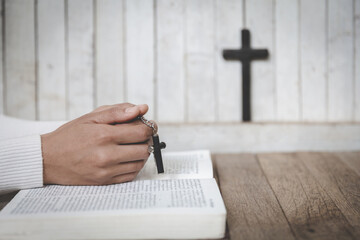 Hands of a Christian woman holding a cross while praying to God.Religious beliefs, Copy space.