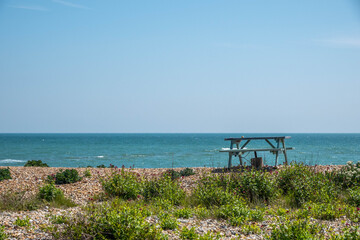 rustic wooden picnic bench on the beach by the sea