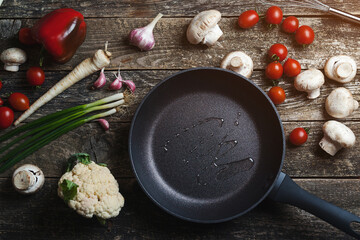 Food background on dark wooden table. Ingredients for cooking food with black pan. Top view, copy space.