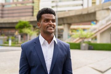 Portrait of African businessman outdoors in city smiling and thinking