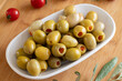 Green olives stuffed with peppers. Tasty organic green olives in the plate. Stuffed olives on wooden background