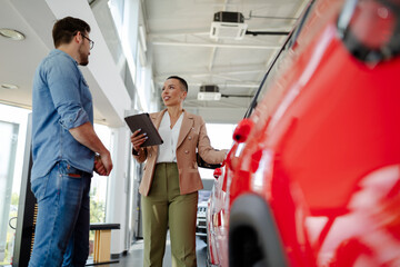 Wall Mural - Handsome man with car dealer in auto show or salon.