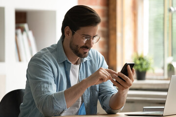 Wall Mural - millennial generation businessman in glasses using cellphone software app, checking emails, communic