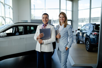 Wall Mural - Two consultants or managers in elegant suit with laptop in arms, looking on camera with smile.