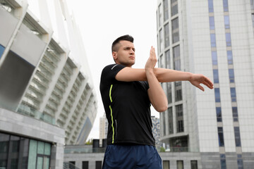 Canvas Print - Young man stretching before morning fitness outdoors