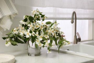 Poster - Bouquet of beautiful jasmine flowers in vase on countertop near kitchen sink