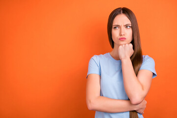 Canvas Print - Photo of sad brown hairdo millennial lady hand chin look empty space wear blue t-shirt isolated on vivid orange color background