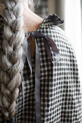 Senior woman white a long braid looking out the window

