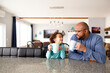 © Jennifer Bogle/Stocksy - Laughing Father and daughter sit together at breakfast bar with drinks