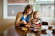 © Jennifer Bogle/Stocksy - Mother and daughter add colorful sprinkles to sugar cookies